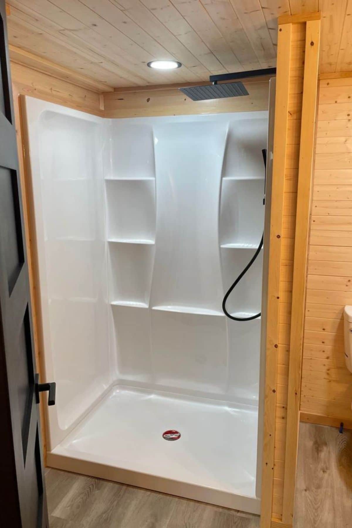 white shower stall with built in shelves inside wood wall