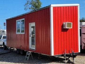 Red tiny home with white trim and air conditioner on end