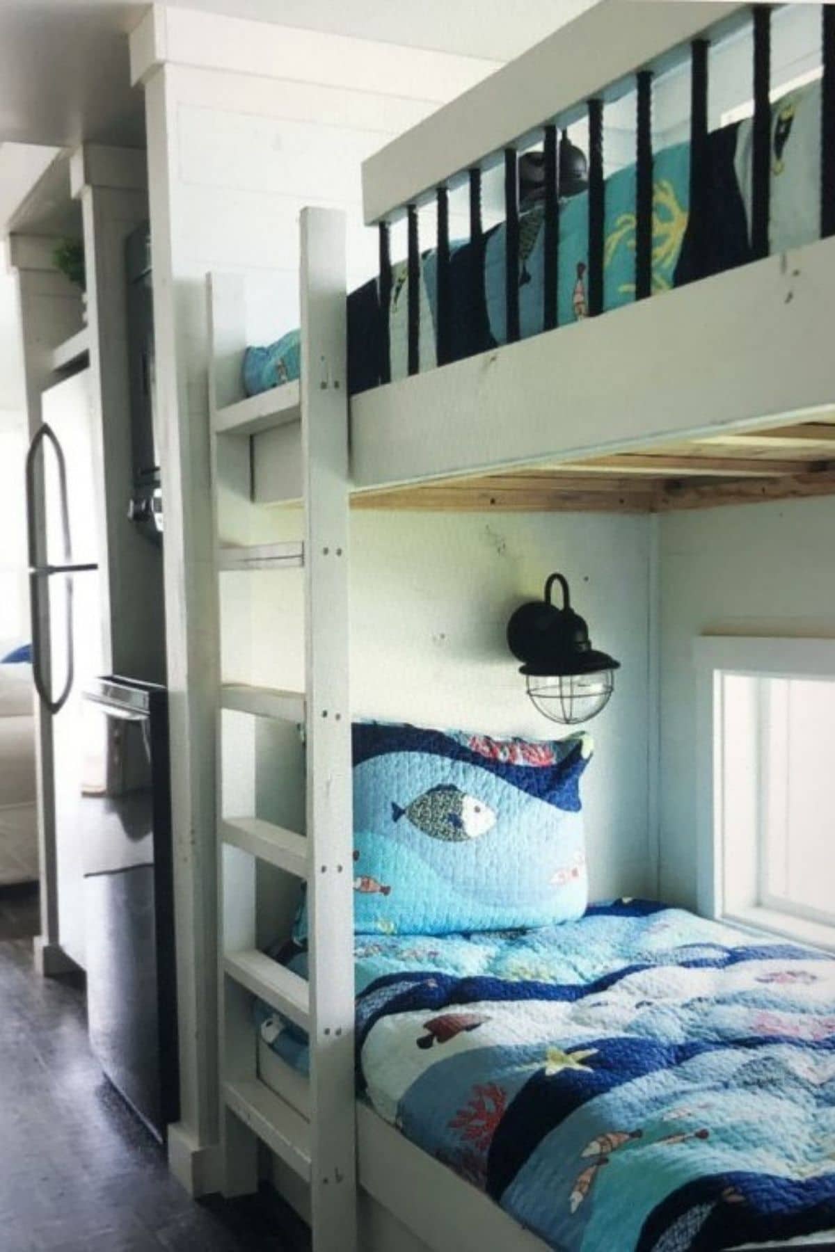 white bunkbeds with blue bedding next to refrigerator