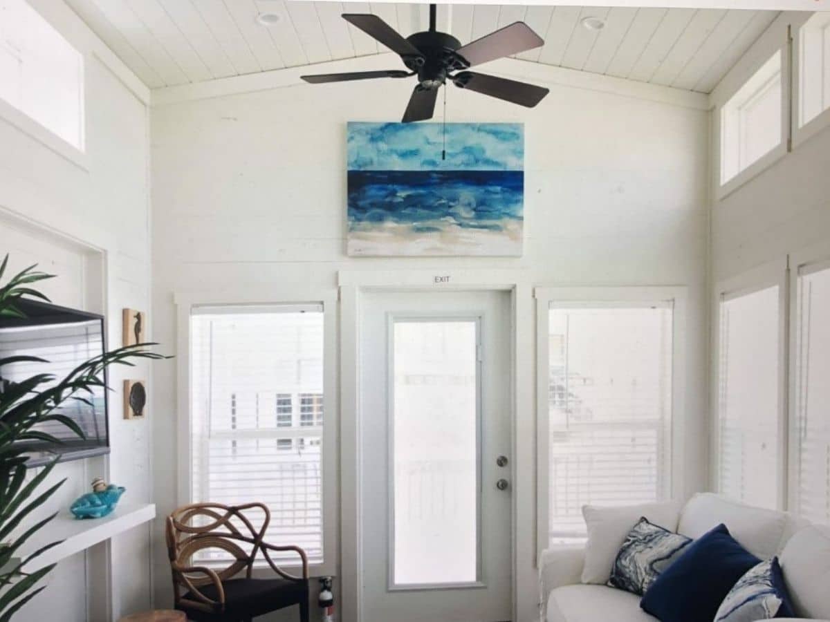 white interior tinyhome with glass door and ocean painting above door