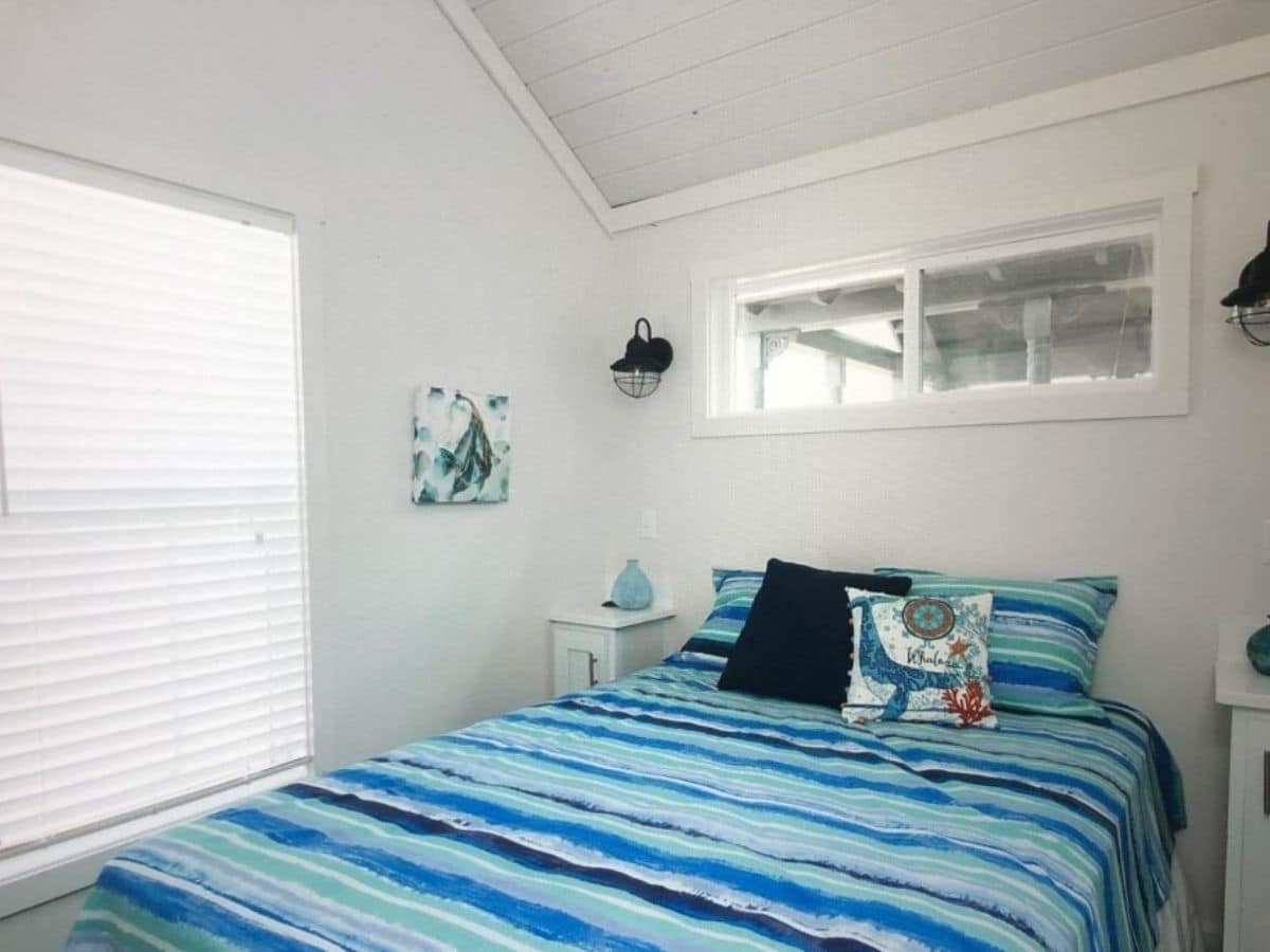 bed against white wall by window with blue bedding