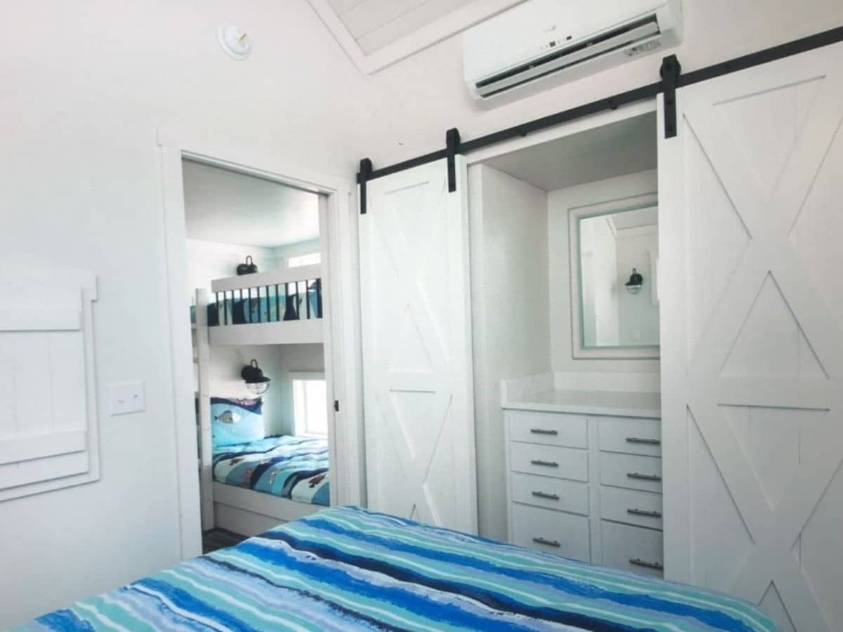 view from bed showing white barn doors over closets at foot of bed and open door with bunk beds outside door
