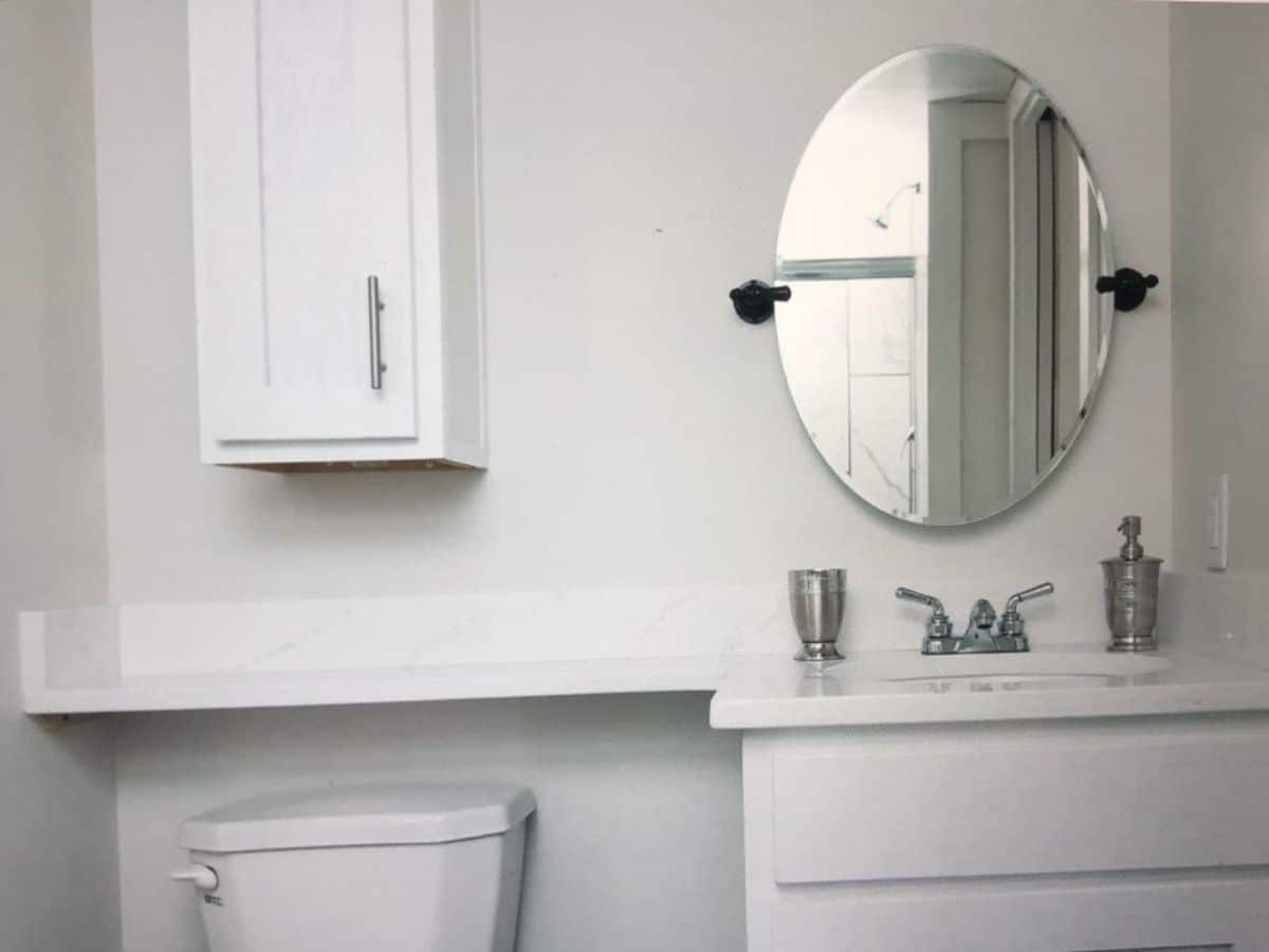 bathroom vanity with shelf above toilet against white wall
