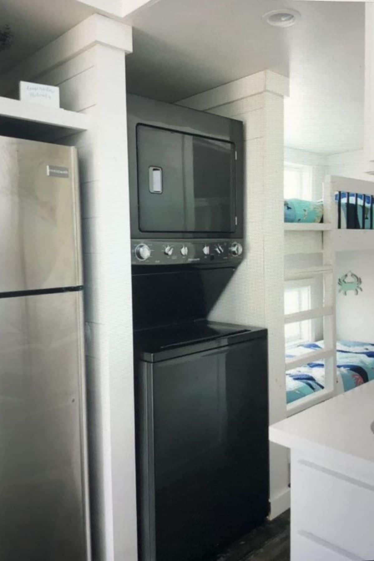black stacking washer and dryer beside stainless steel refrigerator