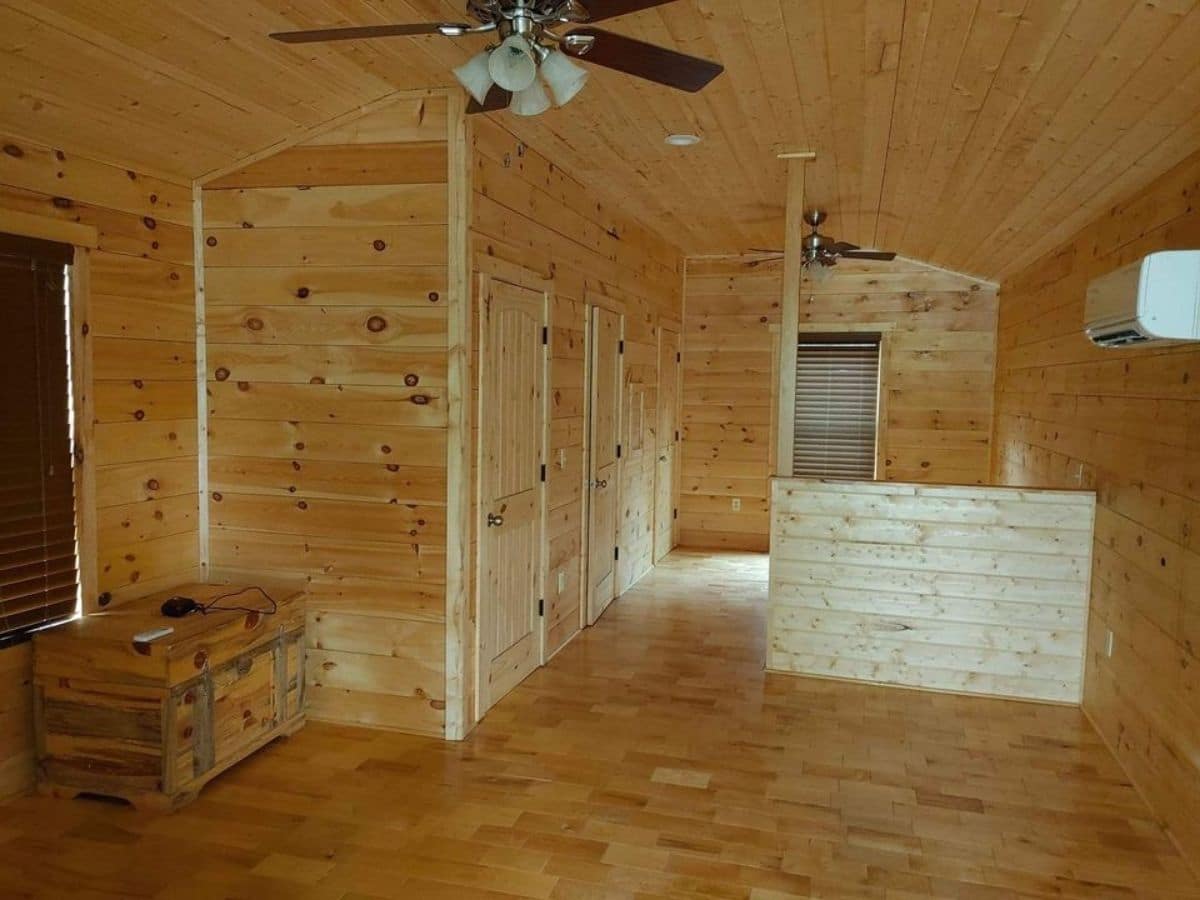 pine paneling and floor inside tiny home with half wall at back of room