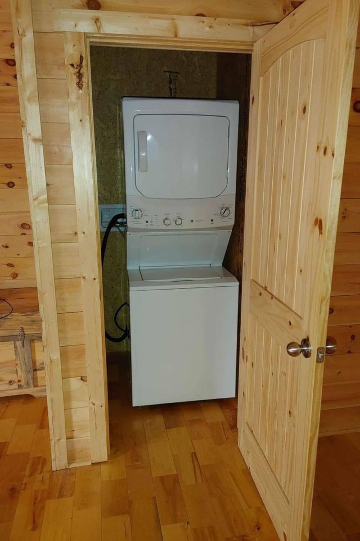 open wood door with white stacking washer and dryer inside