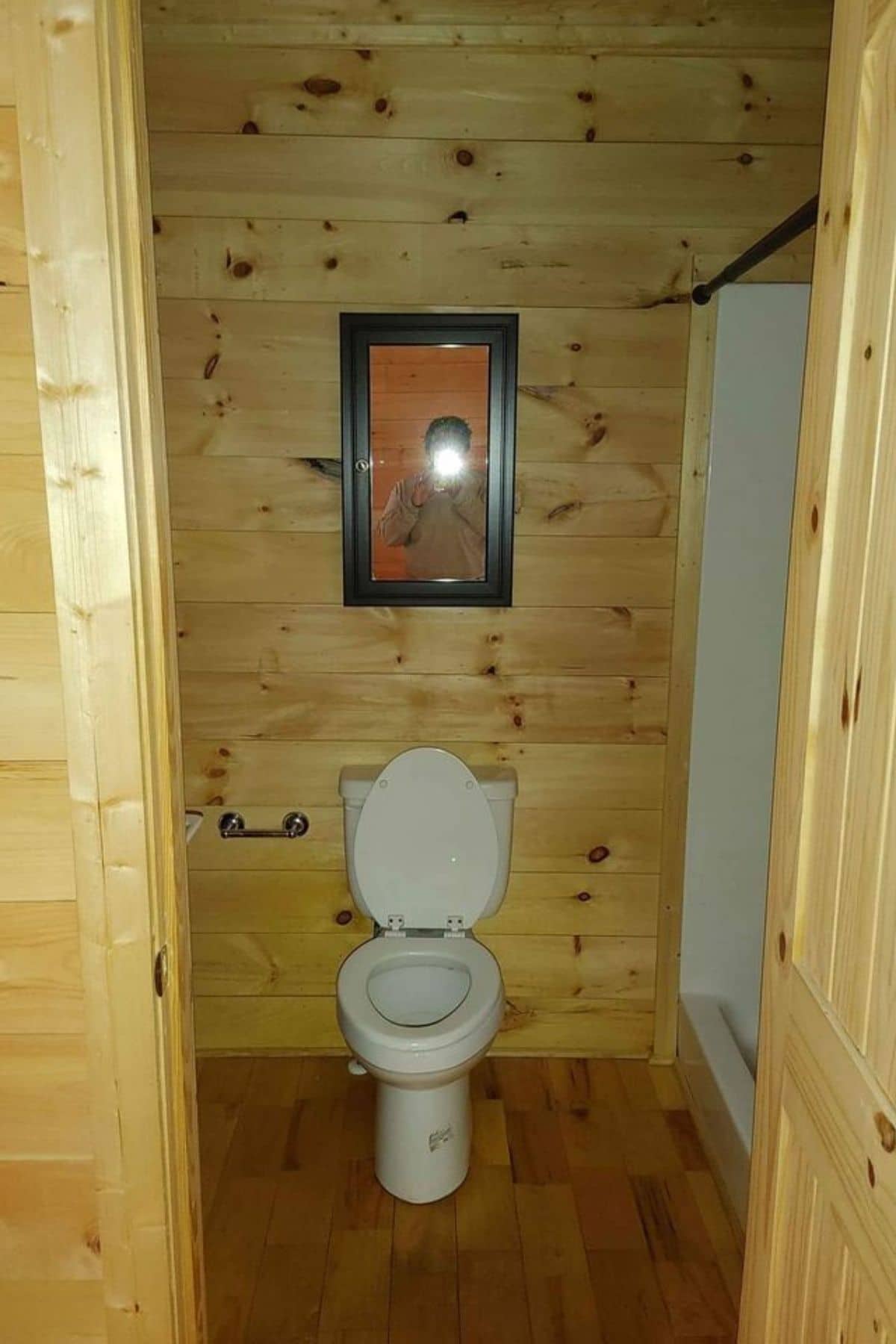 toilet through door with black mirror above and shower to right