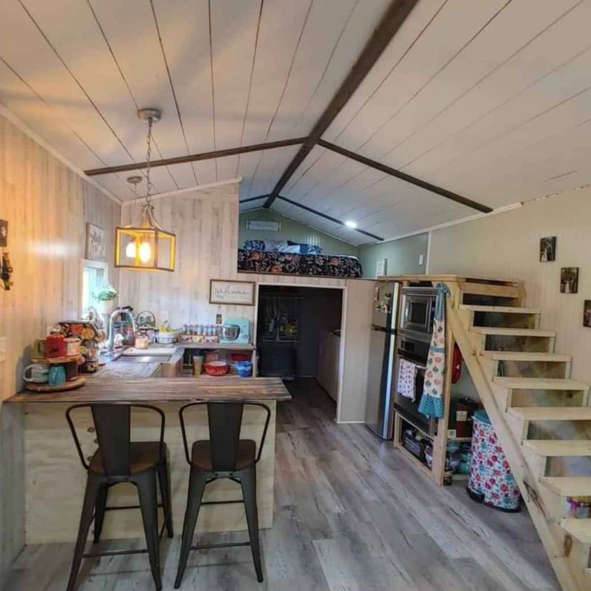 view into back of tiny home with stairs on right and kitchen counter on left