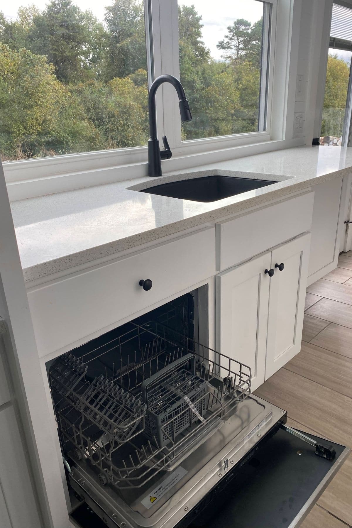 dishwasher open and pulled out underneath white countertop