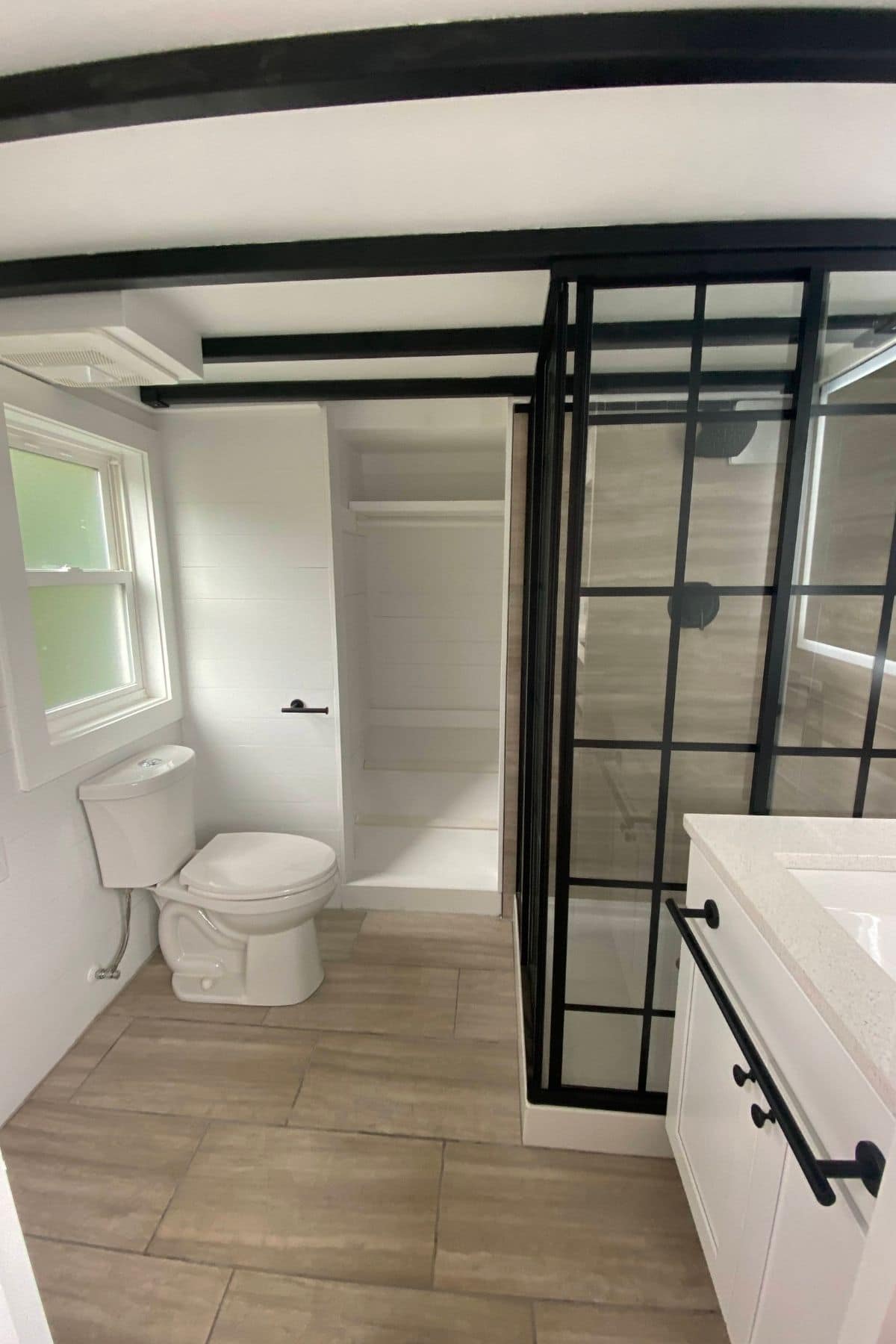view into bathroom with white vanity in foreground and black and glass shower in background