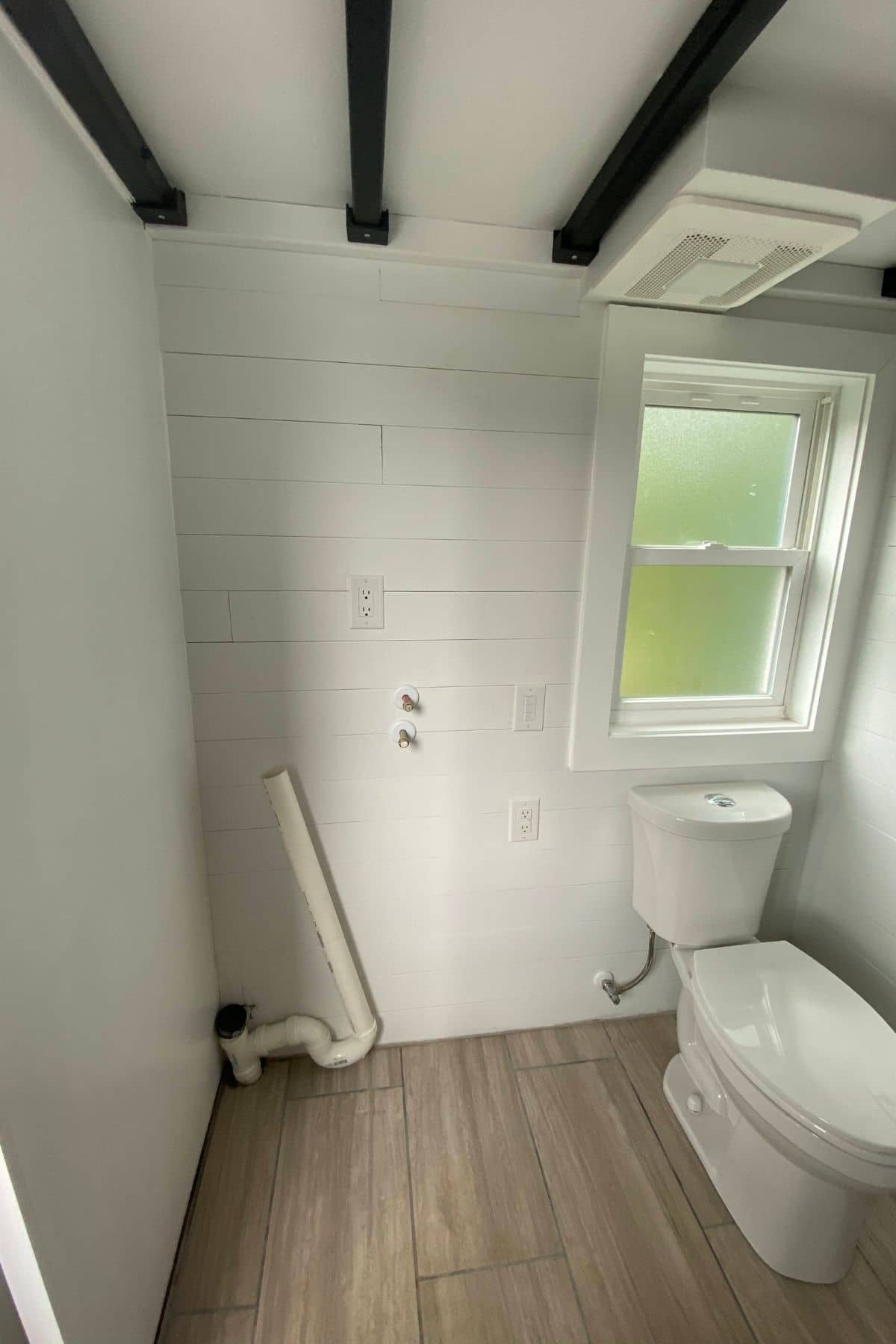 open space with laundry hookups next to white toilet under window