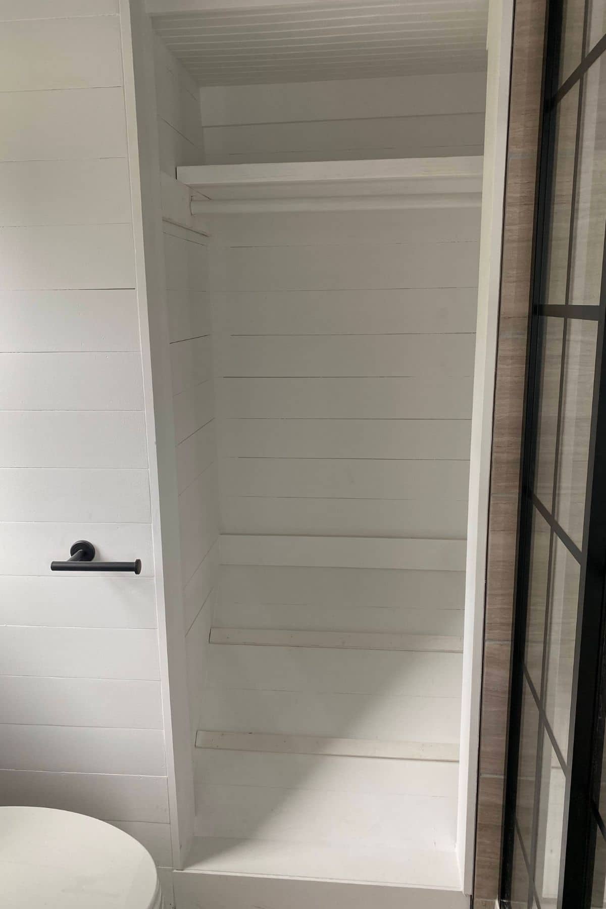open white shelving next to glass and black shower
