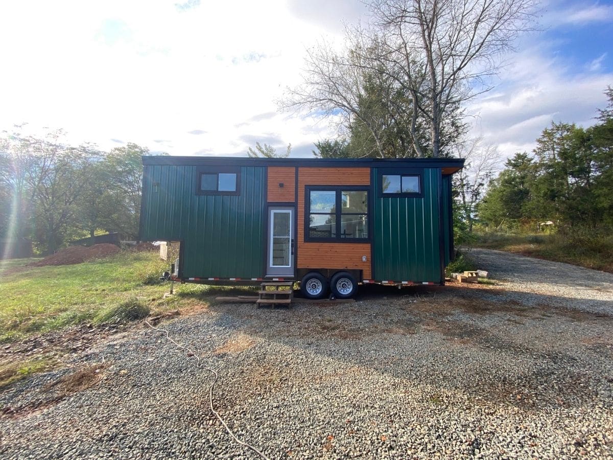 green and wood tiny house on gravel lot