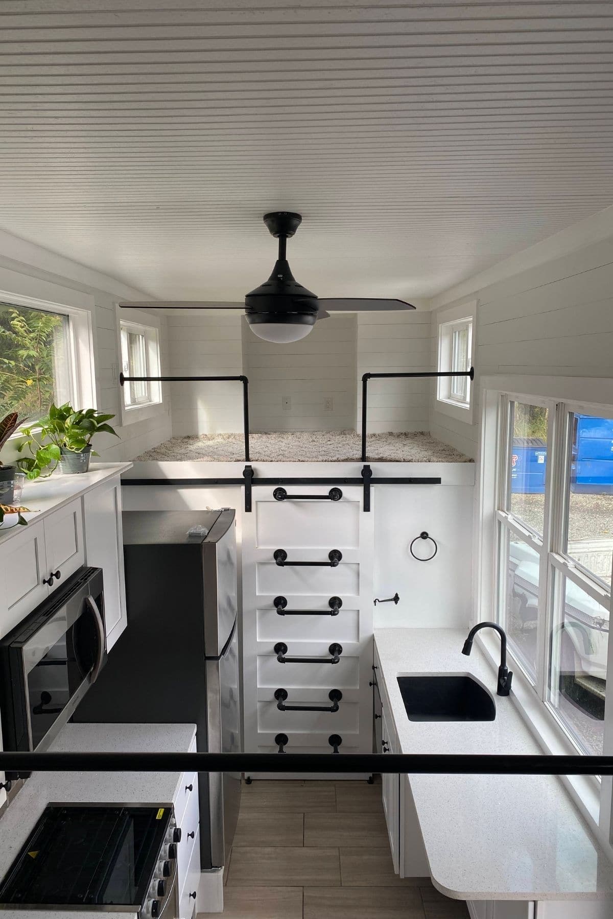 tiny home interior with kitchen cabinets on both sides and white door to bathroom at end