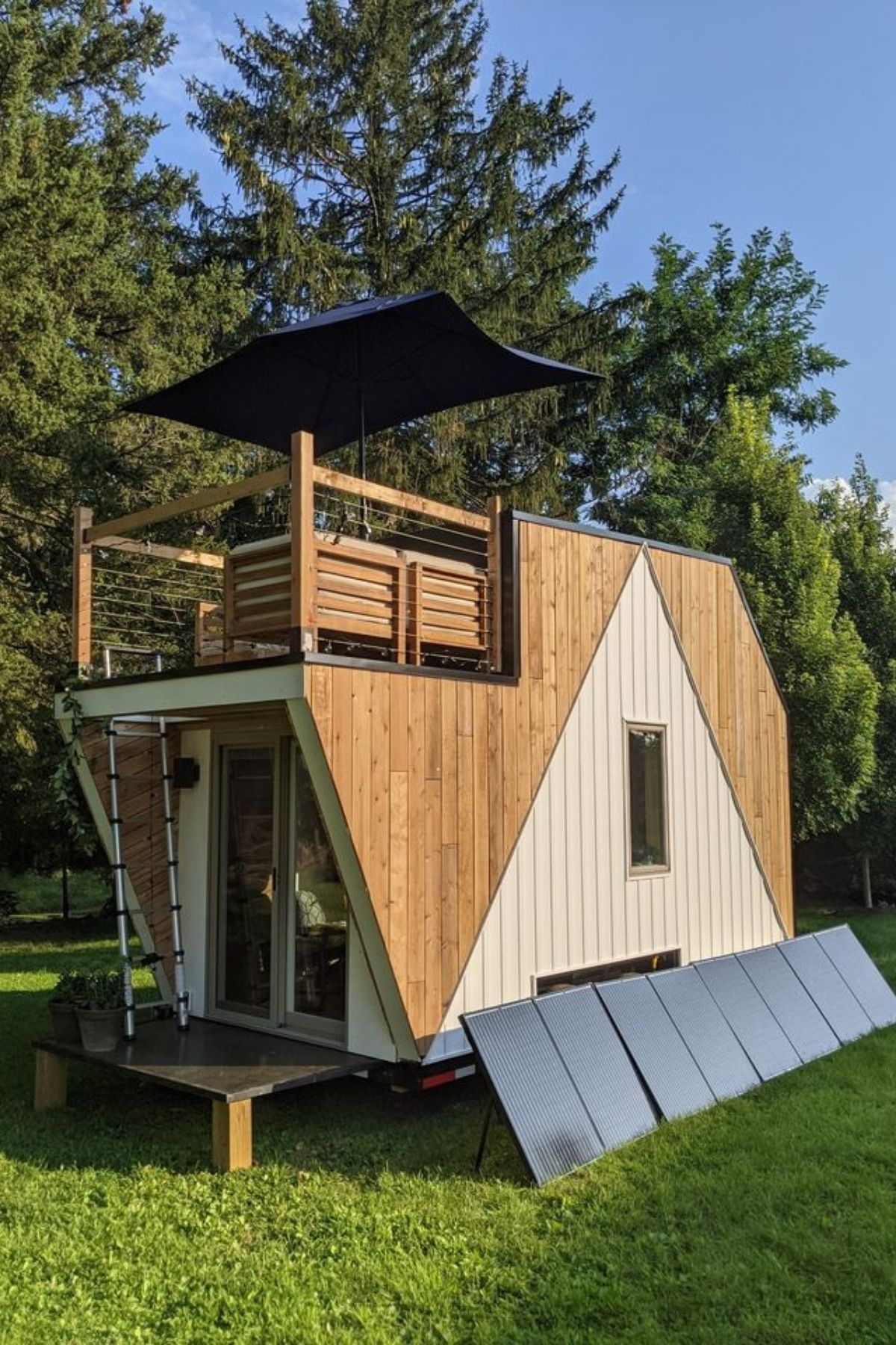 two toned light wood tiny home with solar panels on side