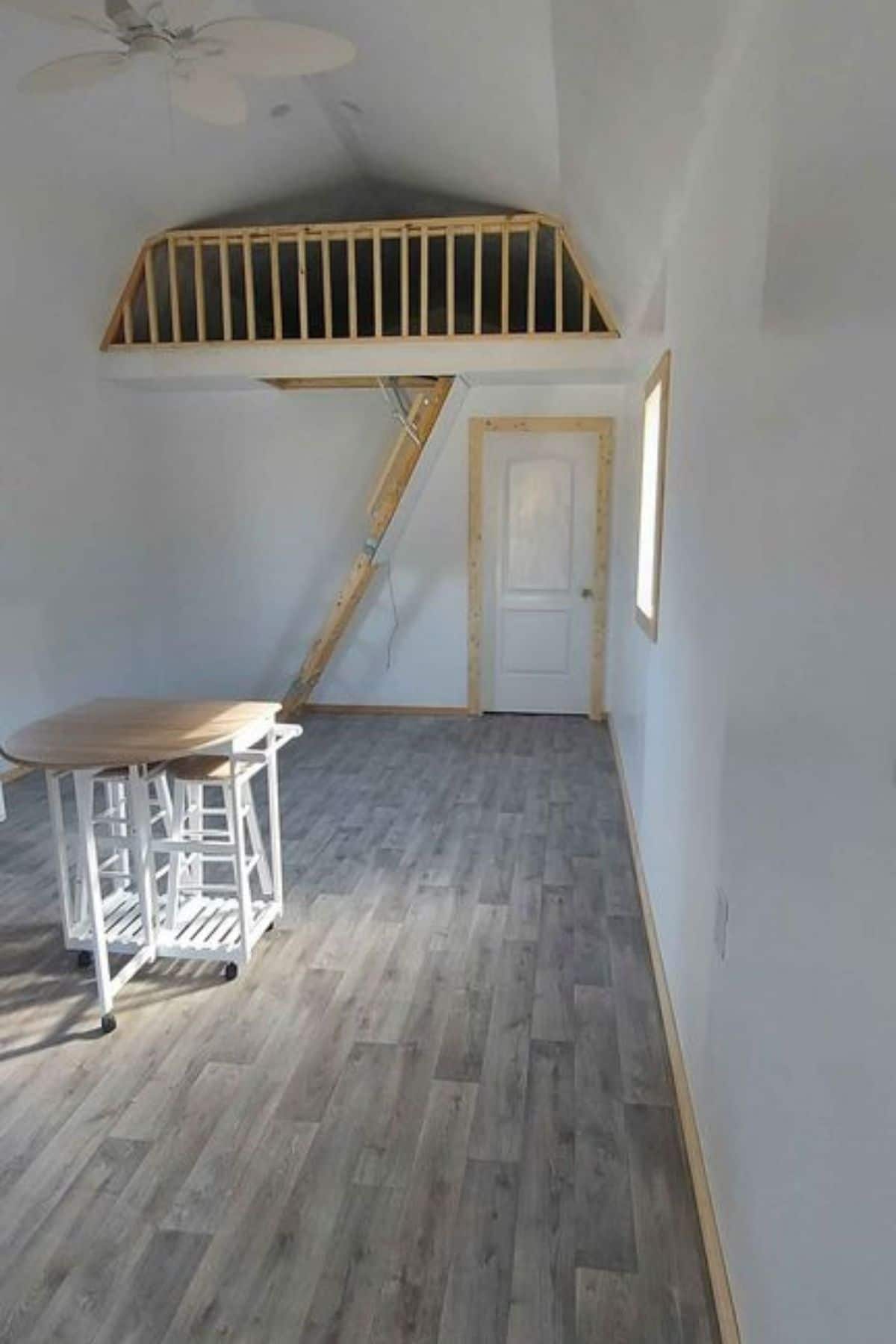 gray floor in white cabin with loft at back wall