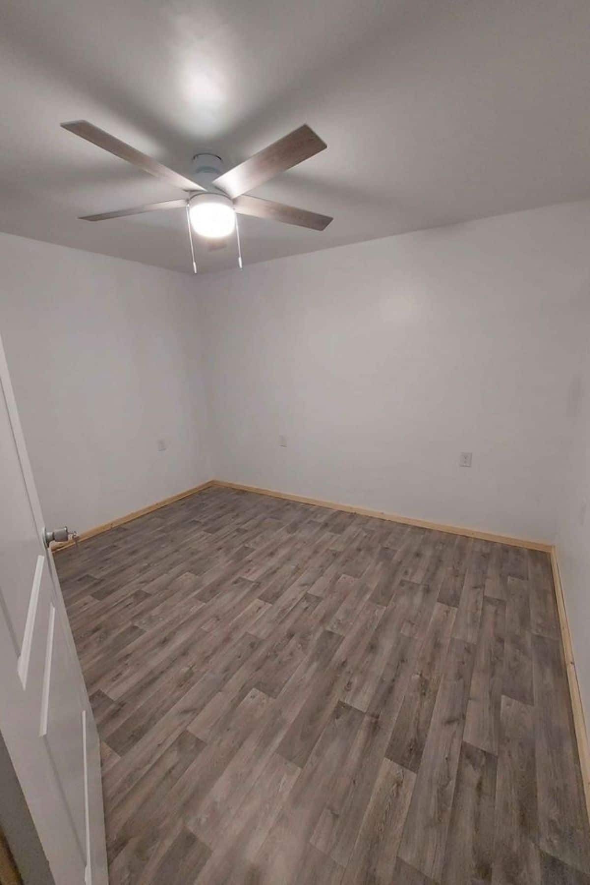 gray floor with white walls and ceiling fan in middle of room