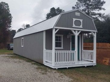 gray shed with teal front door and white porch