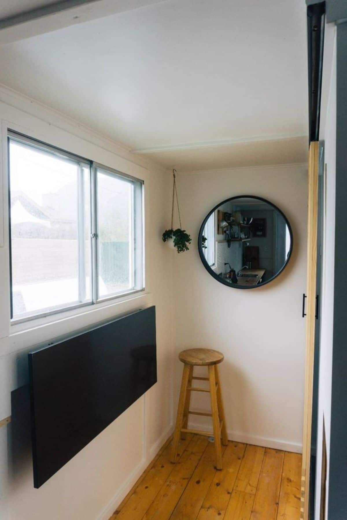 rund mirror on back wall next to large windows above black drop down table