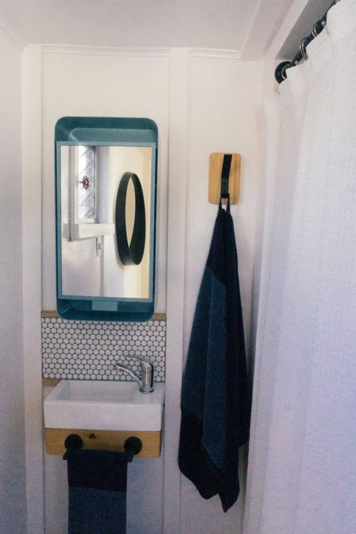 blue towel hanging on hook next to white sink and long mirror