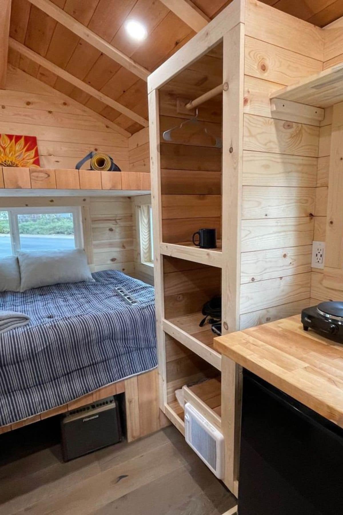 light wood shelves on rigth with bed at back of tiny home