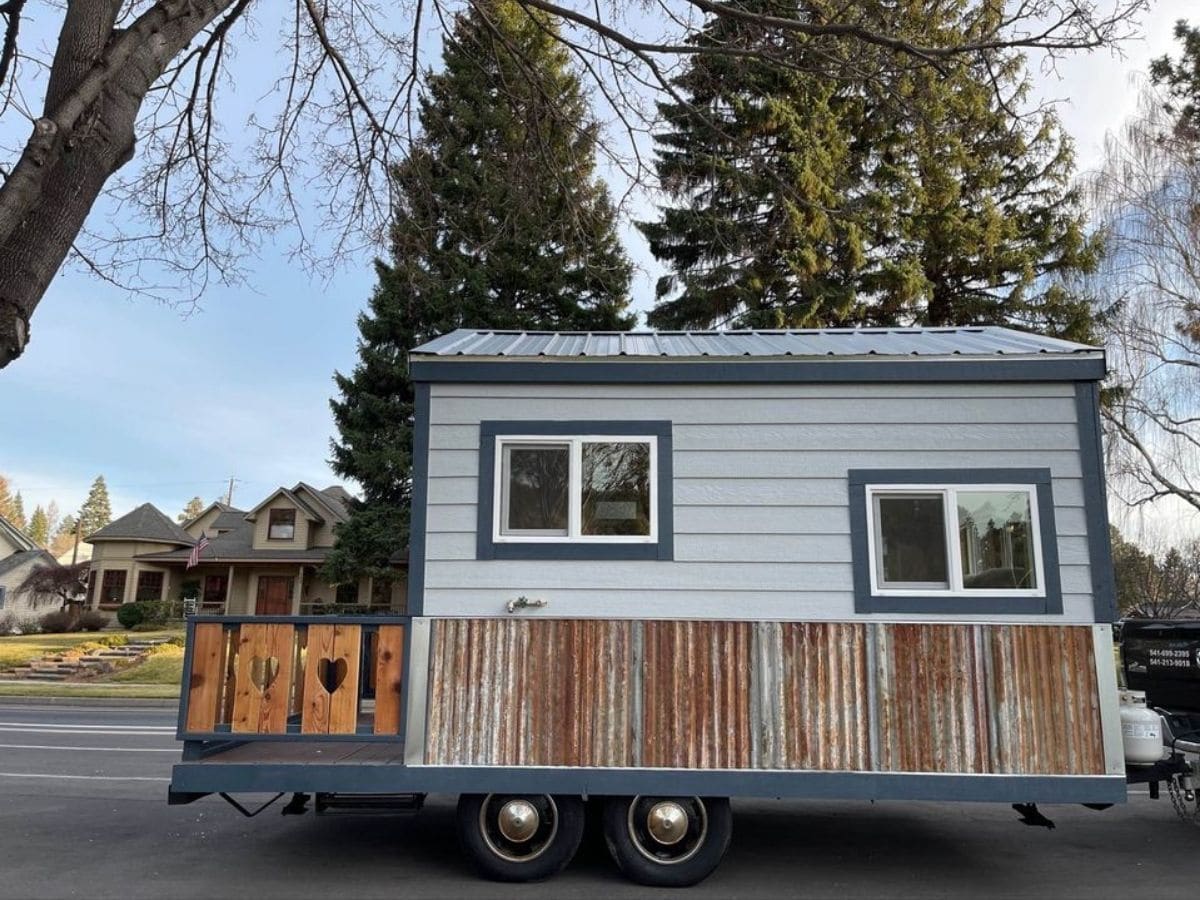 light blue tiny home on trailer with wood slat fence at end