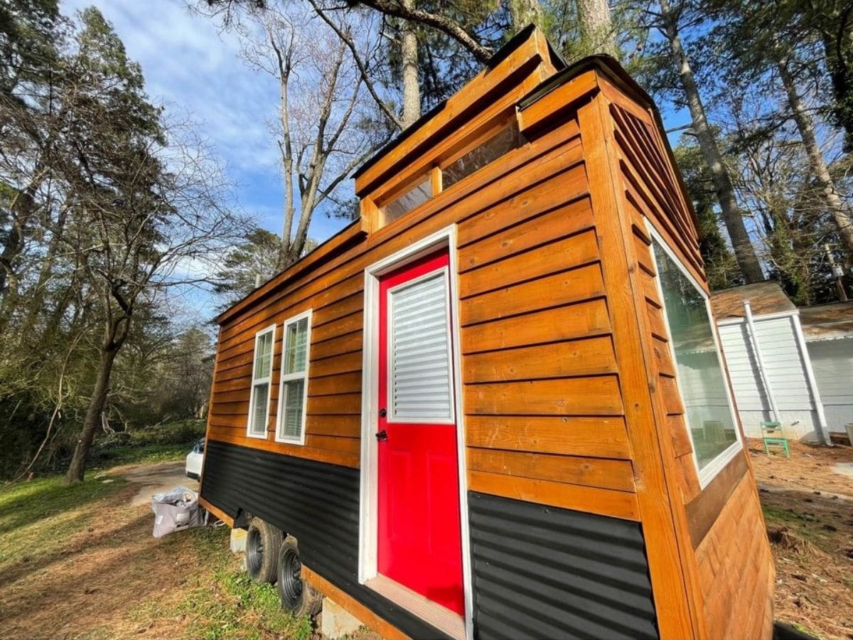 two tone tiny house with wood and black siding and red front door