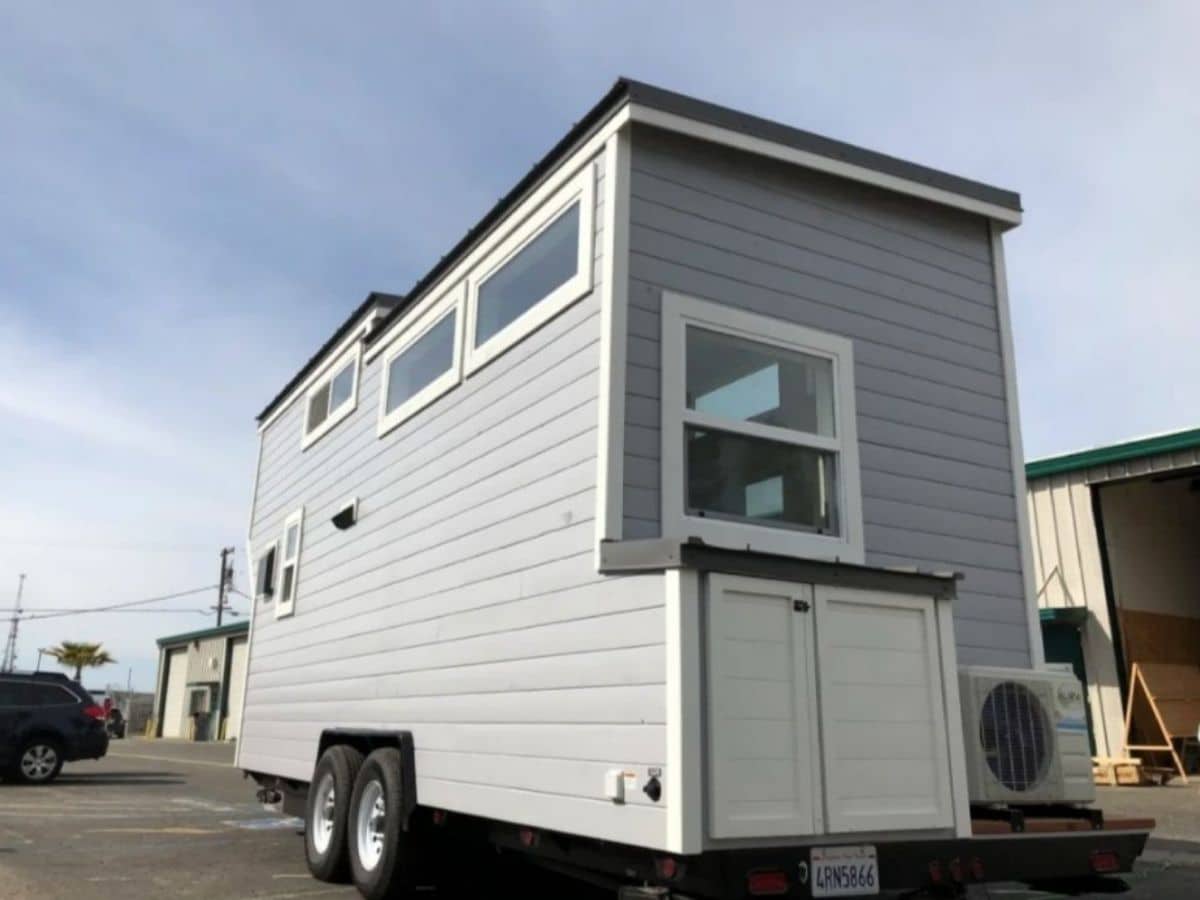 back of light gray tiny home with white trim on windows