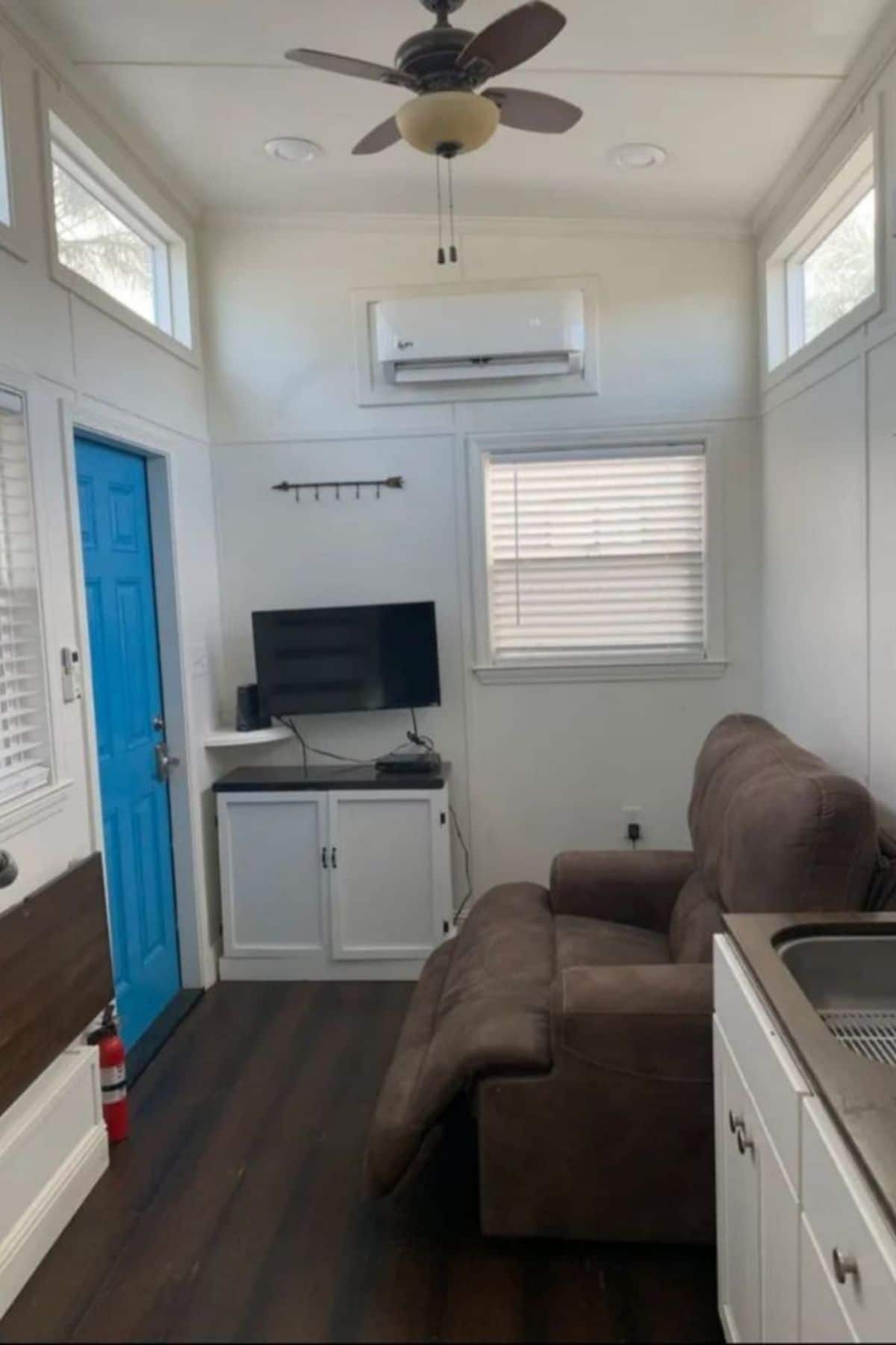 brown recliner against wall across from bright blue door in tiny home