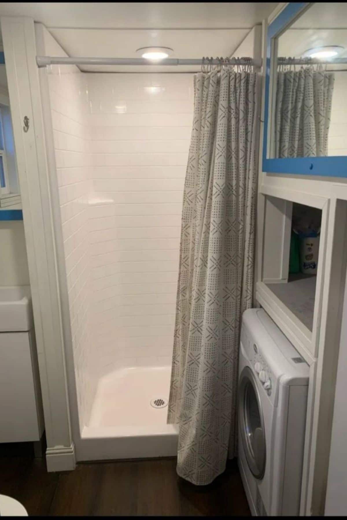 white shower stall with gray curtain at back of bathroom wall