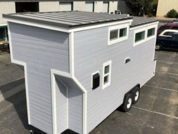 light gray tiny home with white trim on parking lot