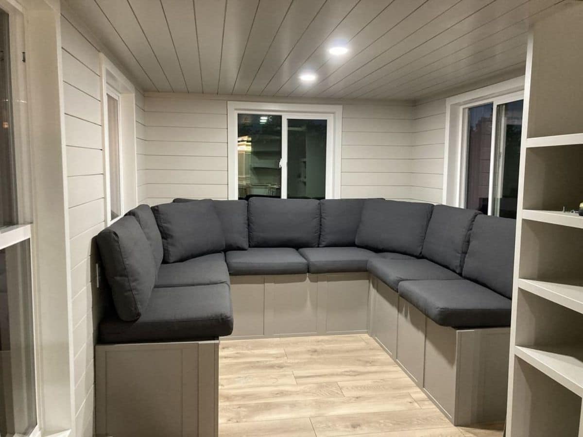 dark blue sectional sofa against back wall of tiny home with white walls