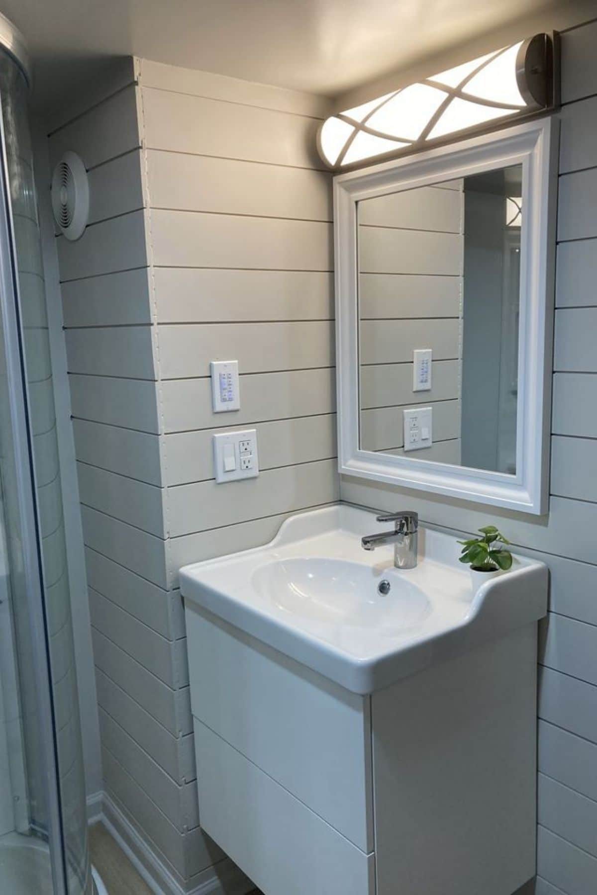 white bathroom sink with white trimmed mirror above