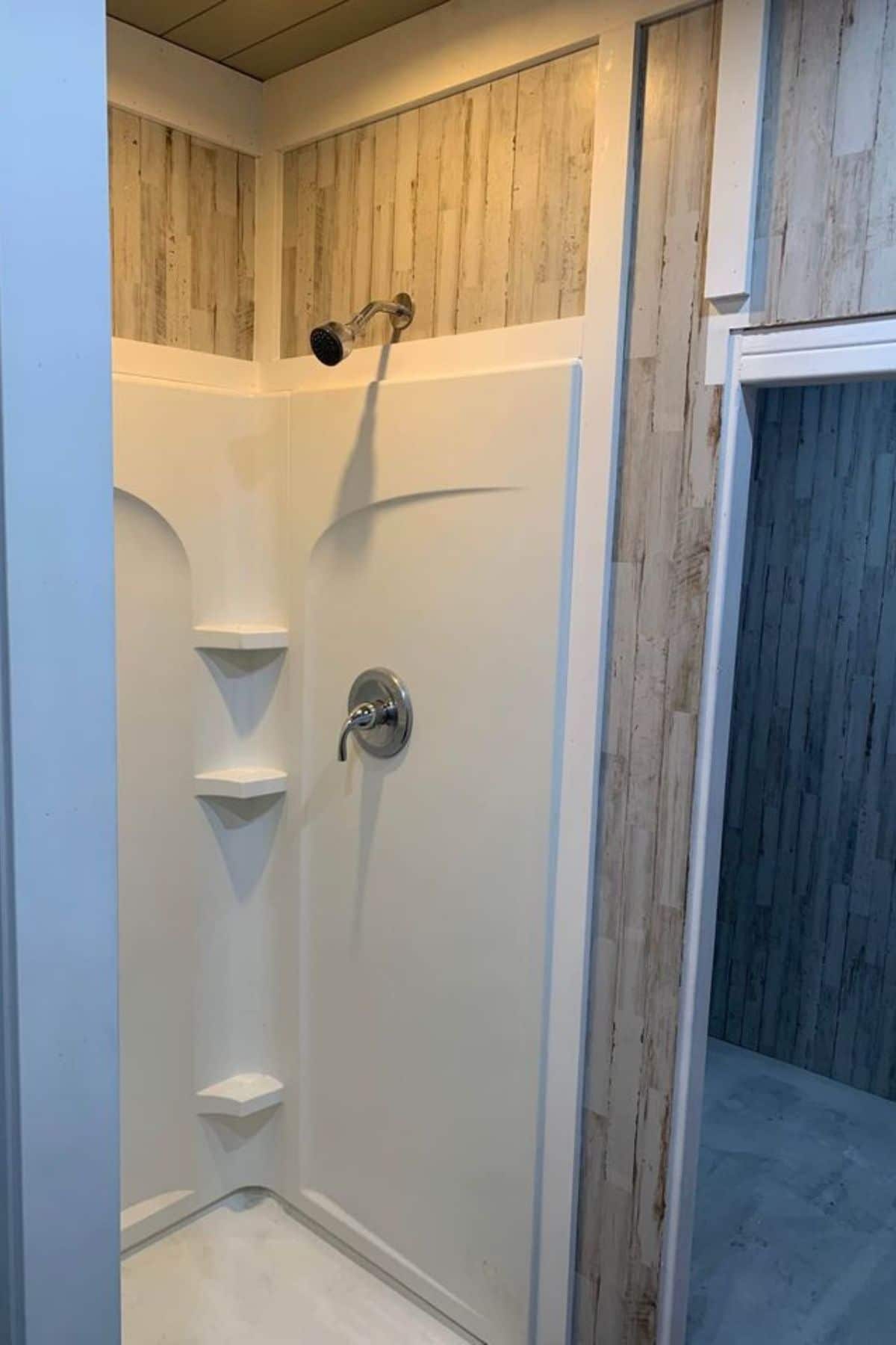 white shower stall with light wood paneling above