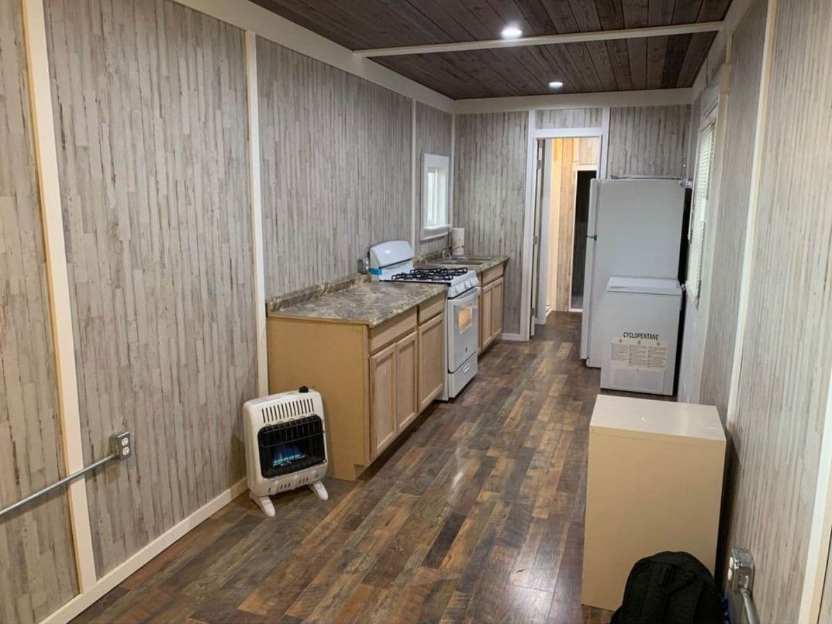view down length of tiny home toward kitchen on left and refrigerator on right