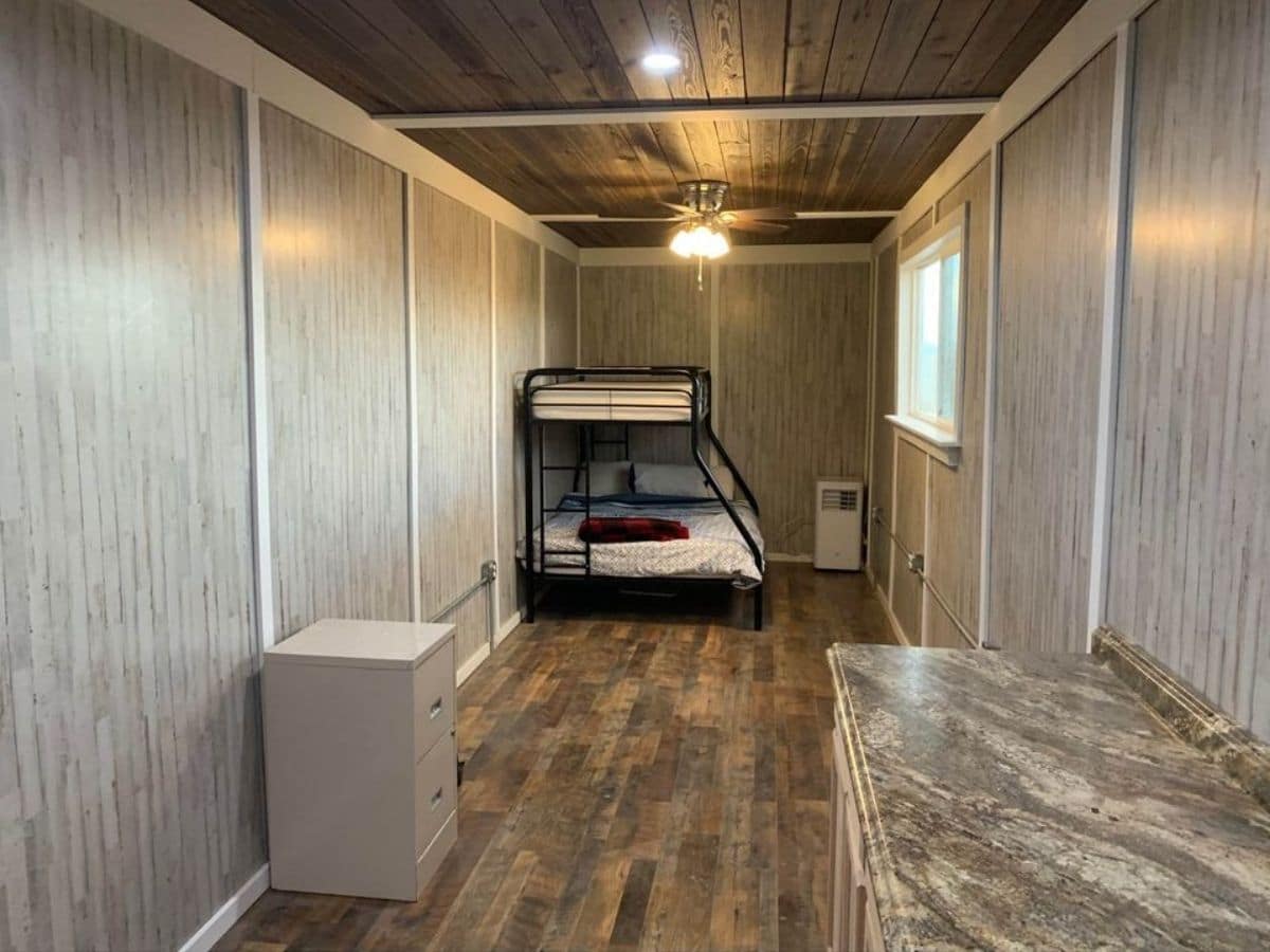 tiny home interior with light wallpaper with black bunk bed in background of image