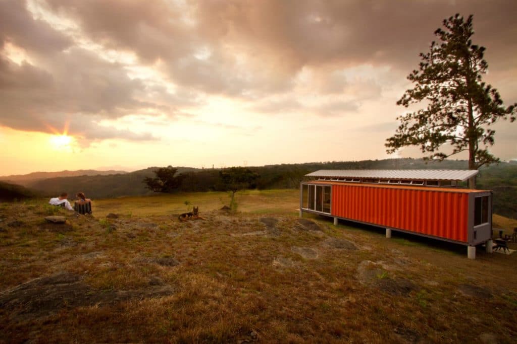 Orange Rectanular Container Home with a wide green view and dawn sky