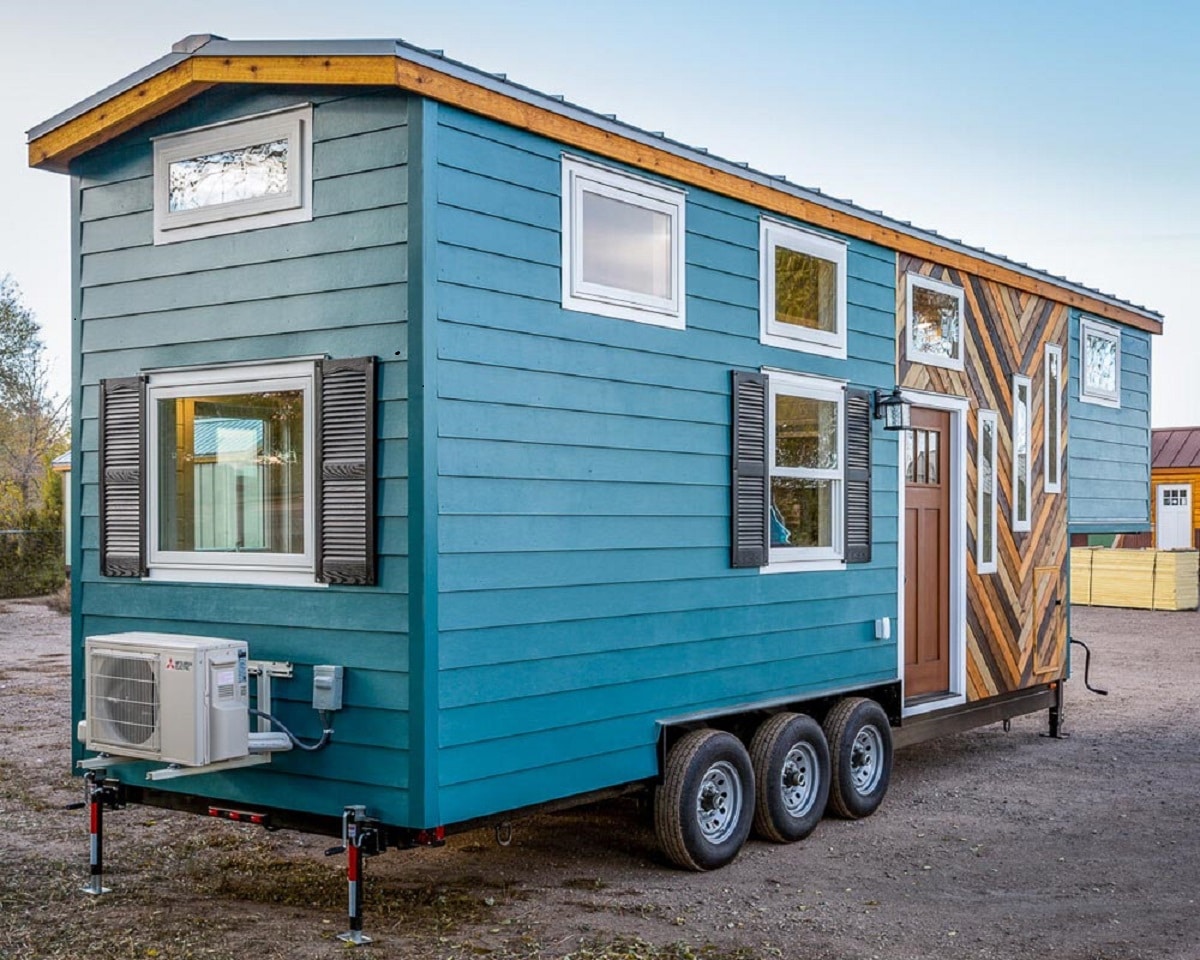 Sideview of a tiny blue house on wheels