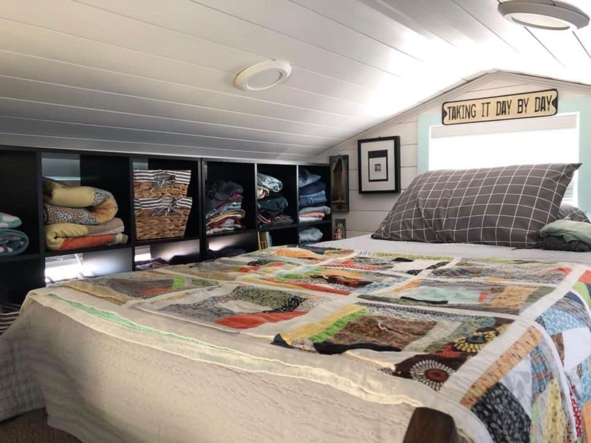 bed in loft with colorful quilt and black cubbies