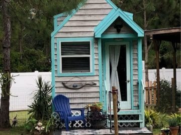 light teal and gray tiny house with small awning over front door