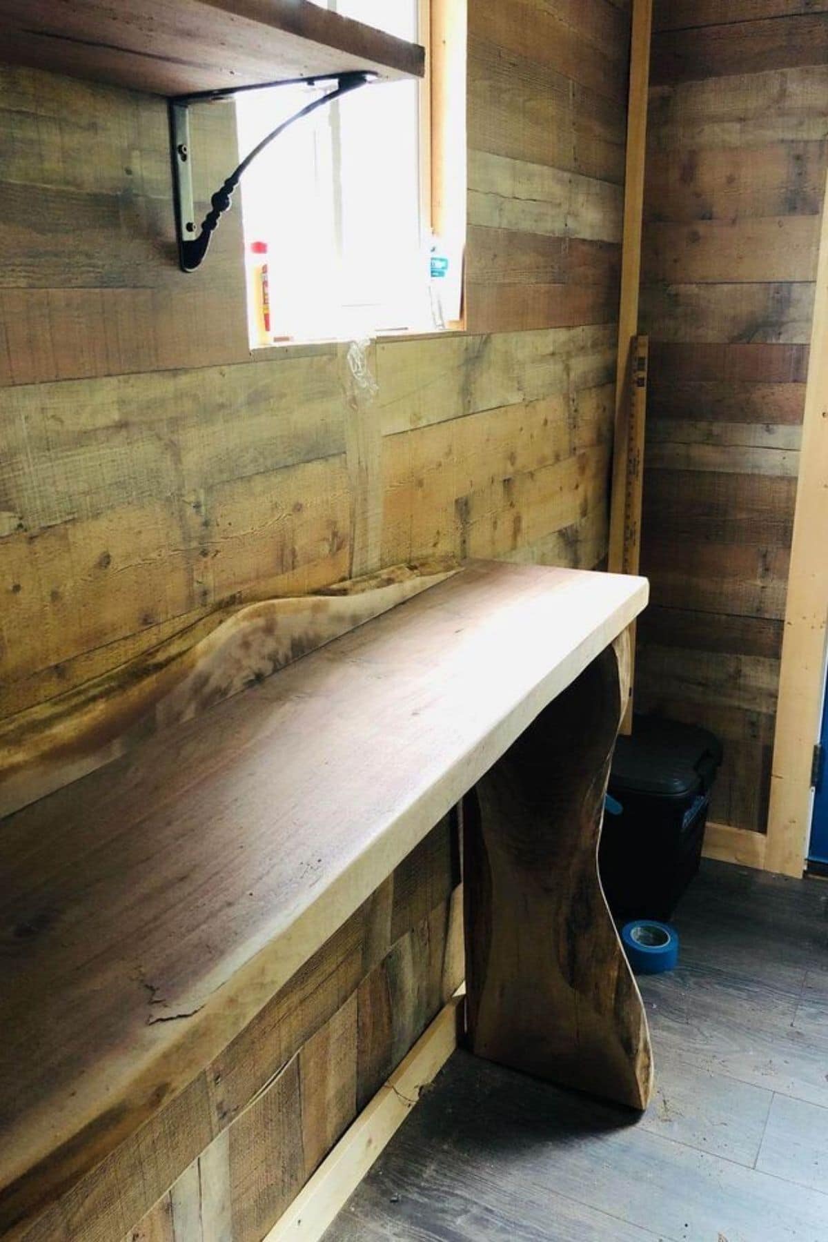 wooden bench built against rustic wood walls of tiny home