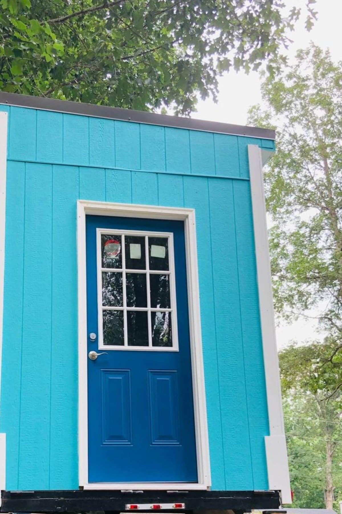 dark blue door on teal tiny home with white trim