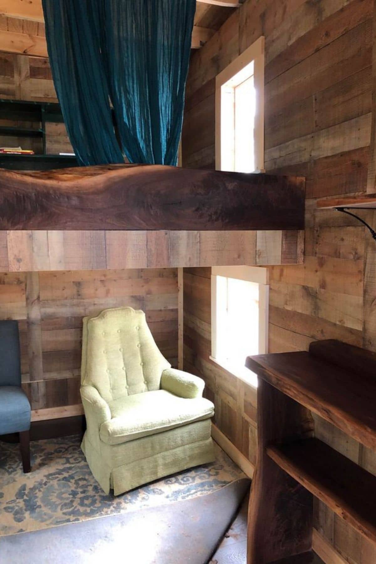 cream chair by window underneath loft in rustic tiny home