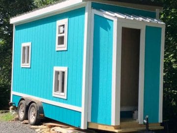 teal tiny home on wheels with white trim and three windows