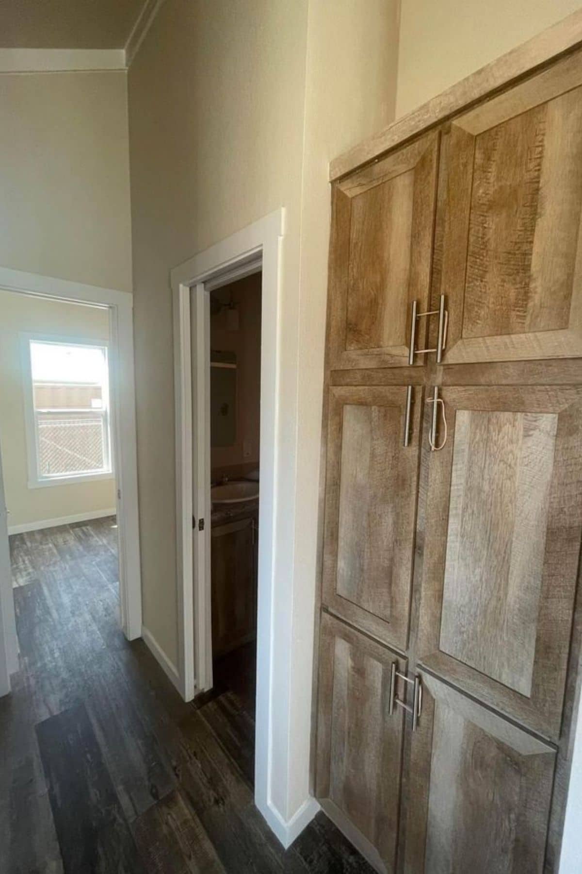 wooden doors against wall next to the bathroom door of tiny home with cream walls