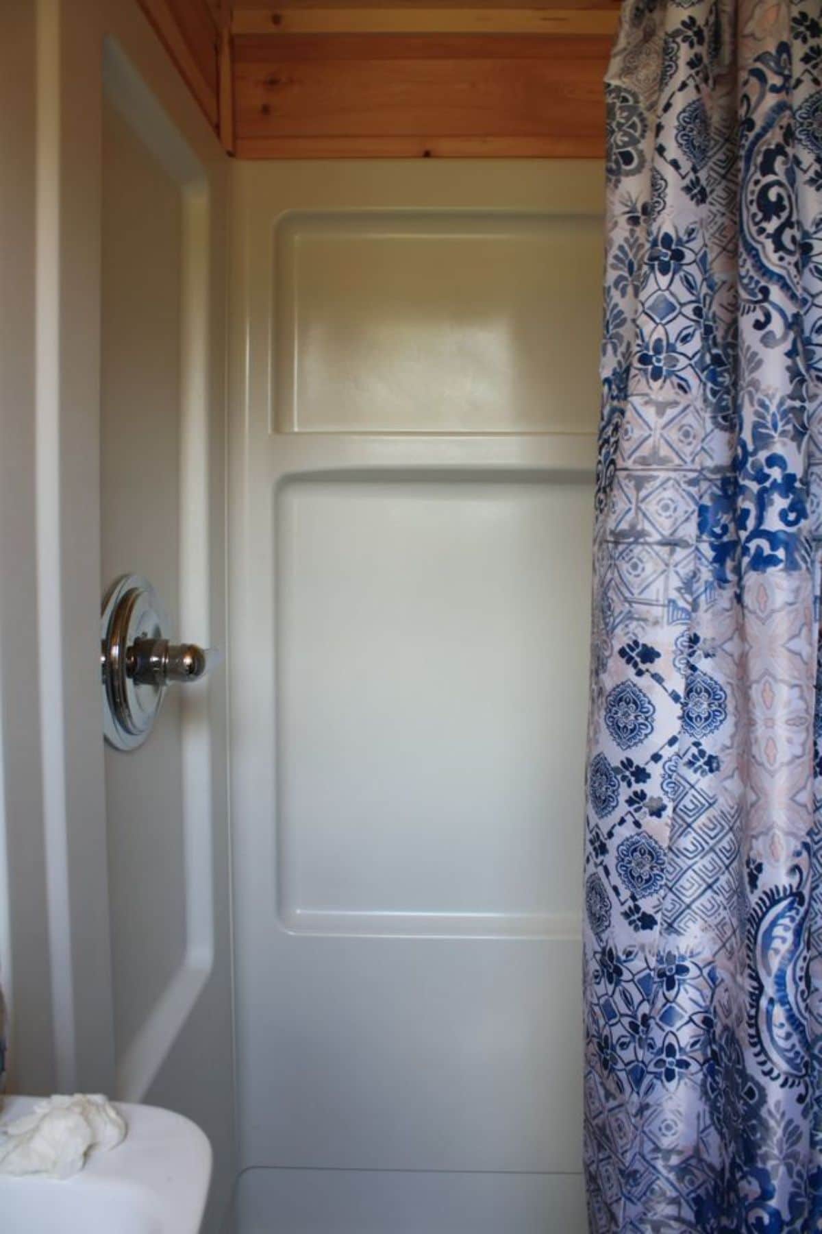 white shower stall with a blue and white shower curtain on right