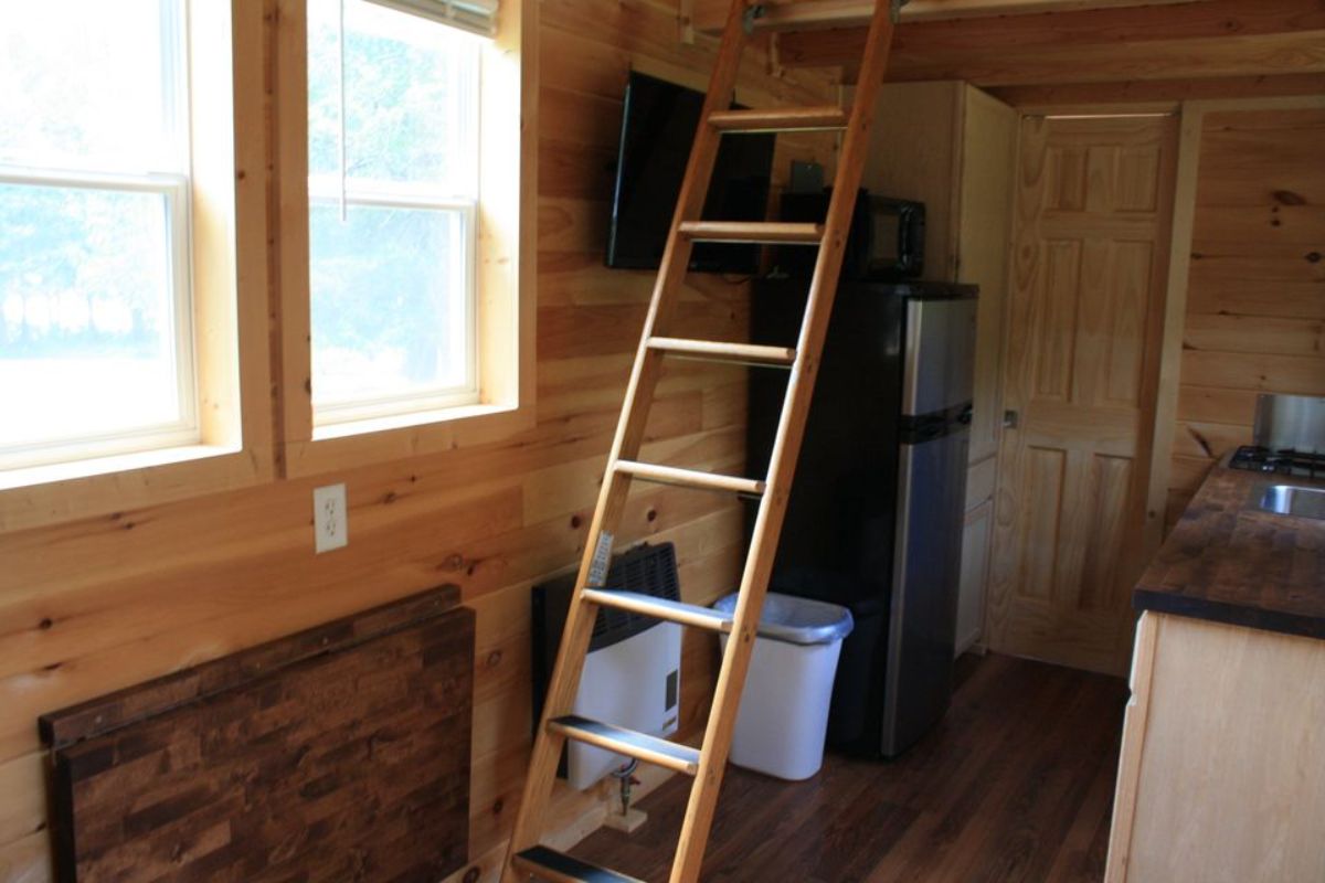 ladder to loft on left of home in front of stainless steel refrigerator