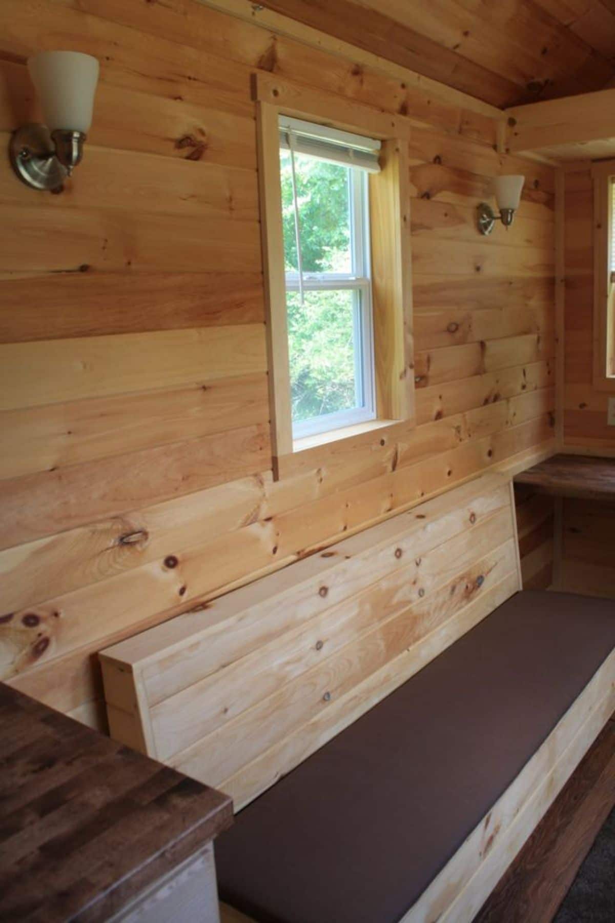 wooden bench seat against inside wall of tiny home