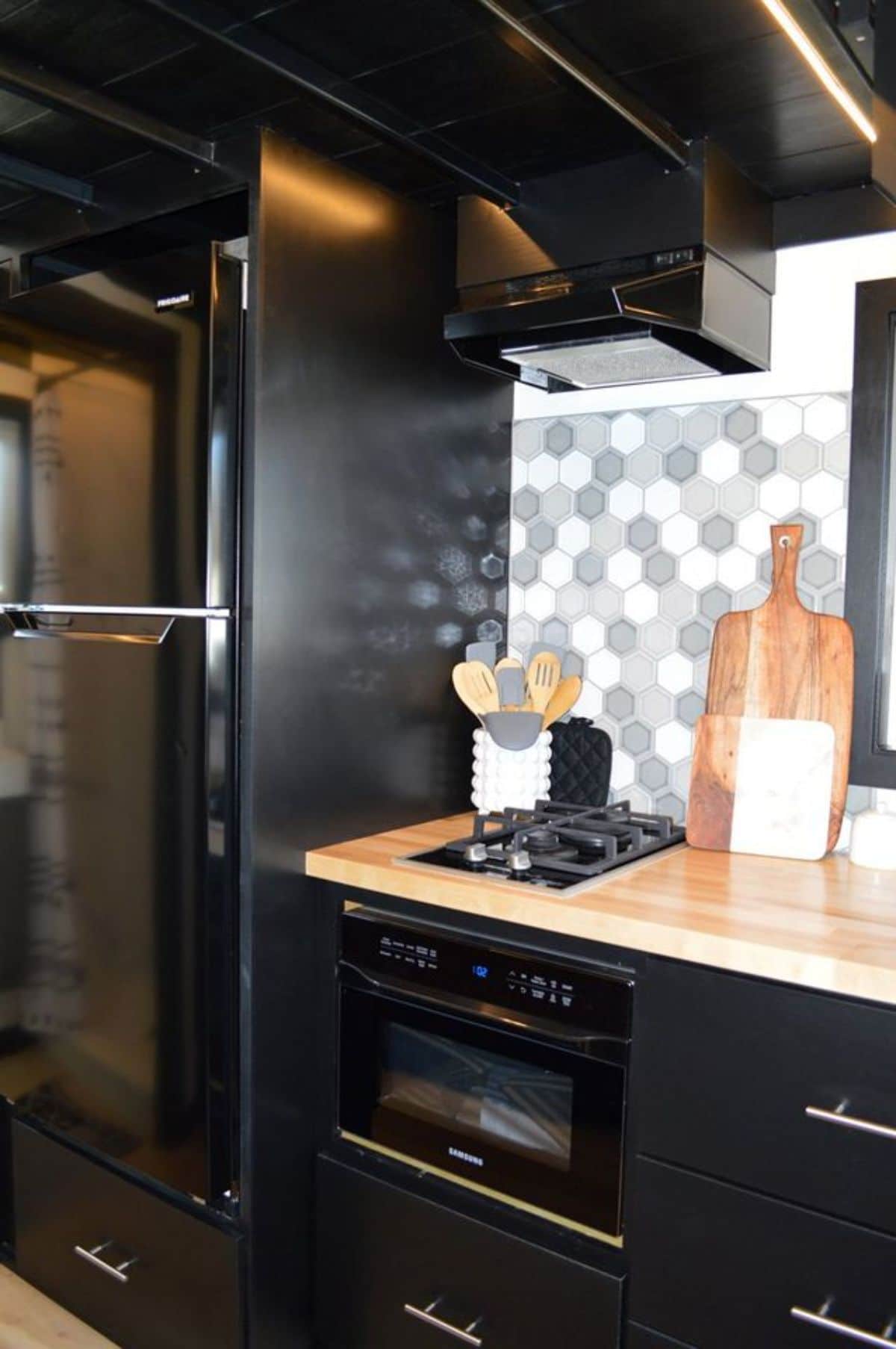 black refrigerator against the kitchen counter with round tiled backsplash