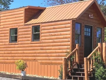 log siding on tiny home with wood porch on front